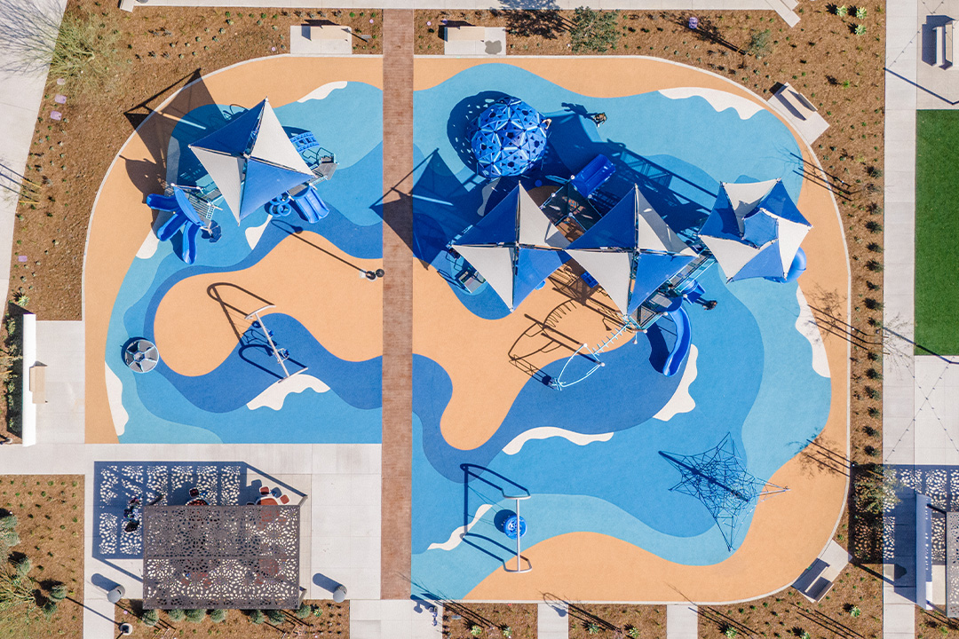 Aerial view of a completed community park with playgrounds, shade sails and colored surfacing