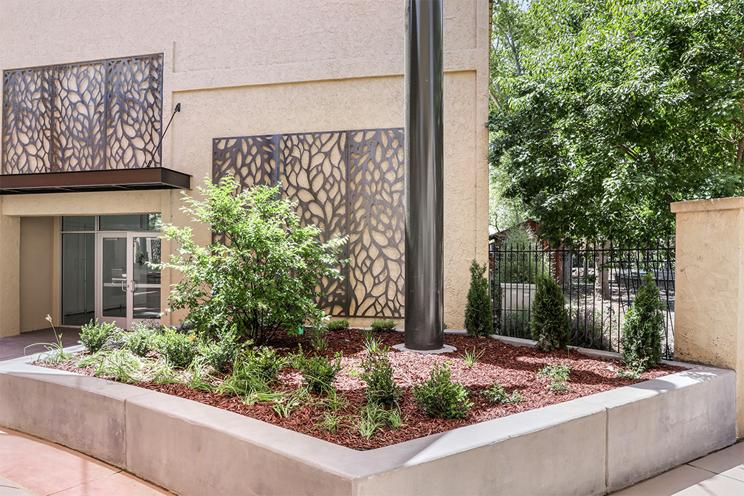 Concrete planter and hardscape with decorative metal screens and landscaping