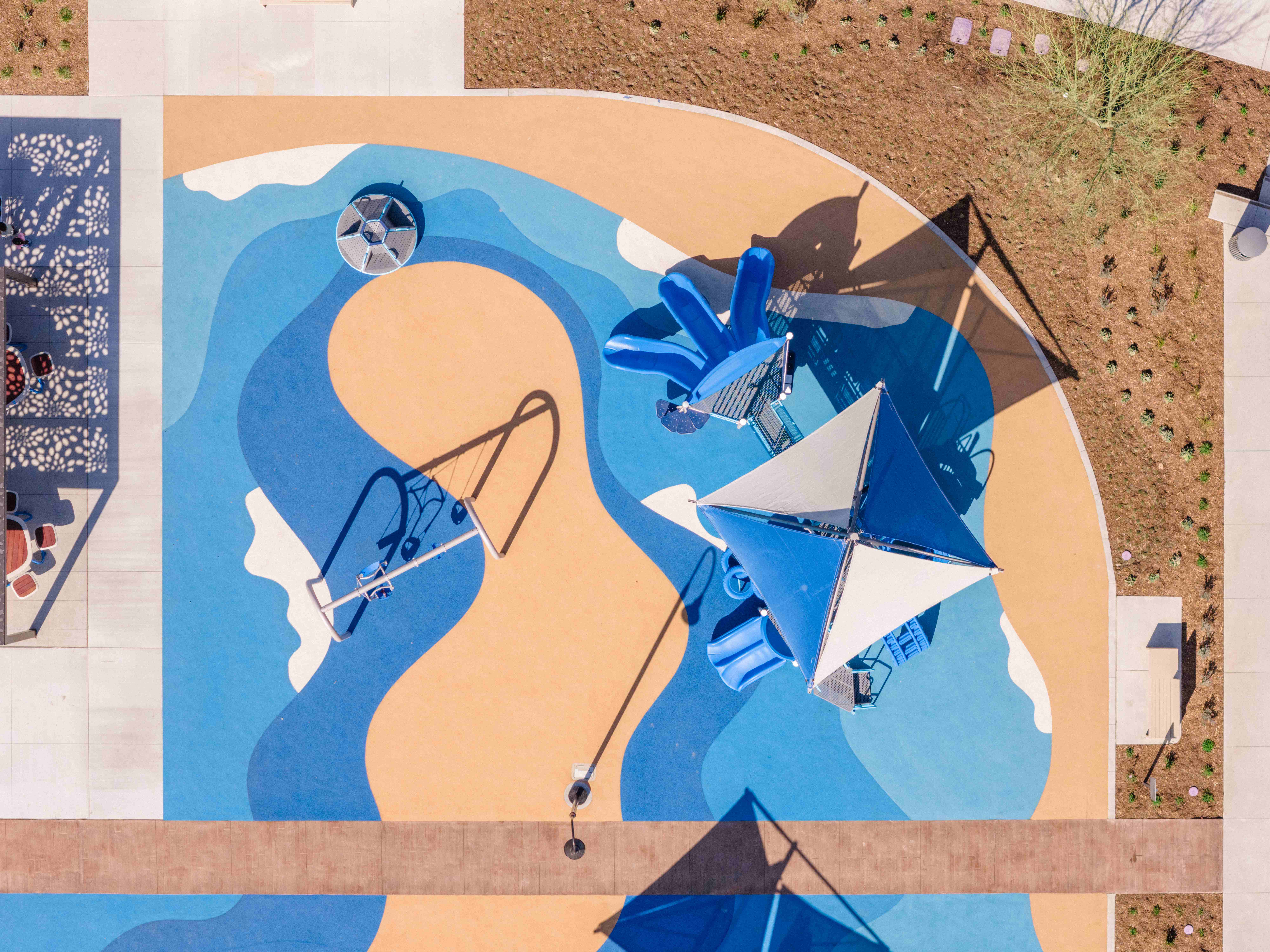Aerial view of a completed playground with poured-in-place surfacing, swings and shade structures